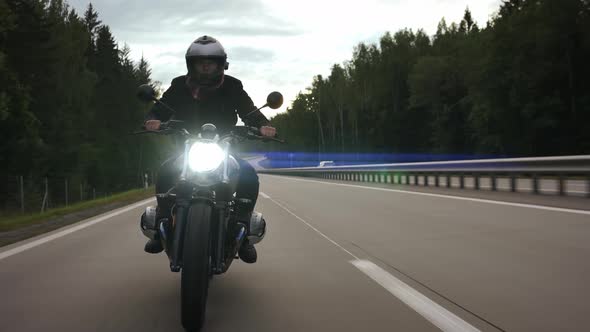 Man Riding Scrambler Motorbike on the Highway Through the Forest Front View alt