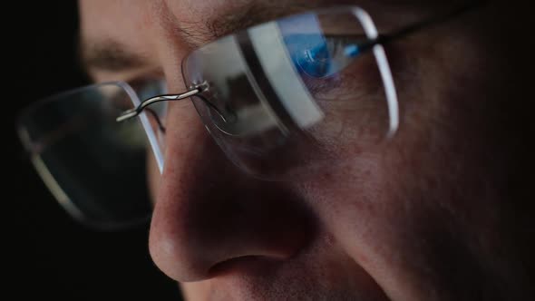 REFLECTION: Close Up of face of adult man in an eyeglasses looking a website