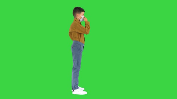 Little Boy Adjusting His Face Mask Looking at Camera on a Green Screen, Chroma Key alt