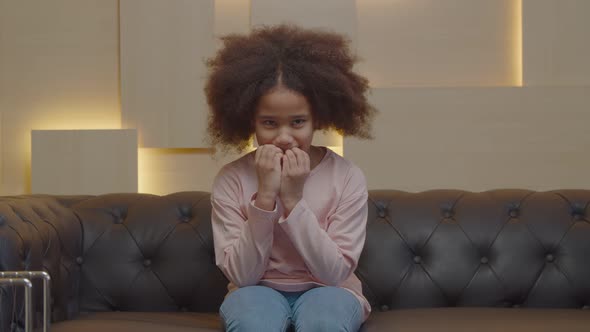 Portrait of Worried Preadolescent Black Girl Nail Biting During Therapy Session alt