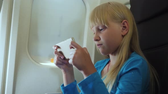 The Child Plays on the Smartphone in the Cockpit alt