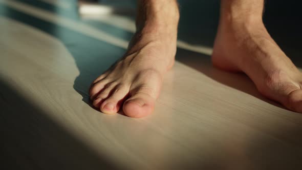 Man stands on the floor with bare feet, camera movement alt