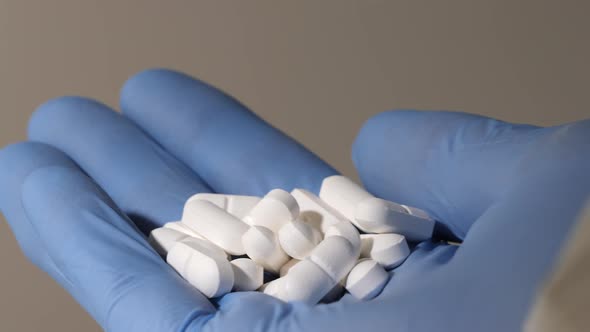 Closeup Shot of a Hand in Blue Latex Gloves Holding Pills alt