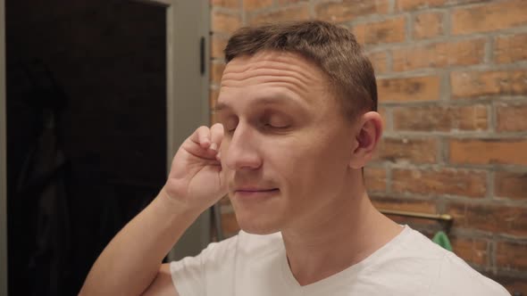 A Man with a Smile on His Face Cleans His Ears with an Ear Stick. alt