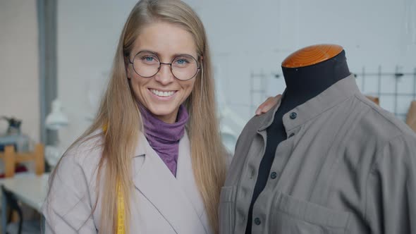 Portrait of Beautiful Young Woman Standing Near Dummy with Handmade Garment Smiling Indoors in alt