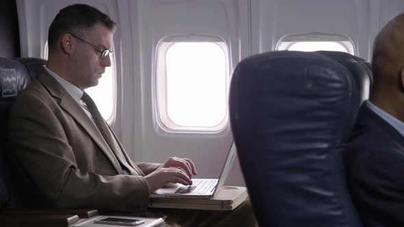 Businessman using laptop computer on airplane