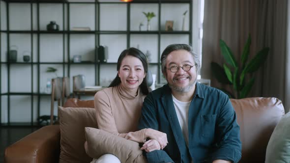 asian lovely husband and wife wear casual cloth sitting on sofa hug embrace together