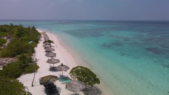 View of blue lagoon beach with umbrellas and sun loungers on maldives island alt