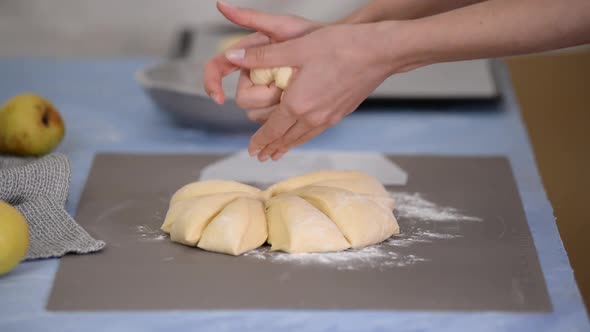Close-up hands forming dough balls for baking buns.