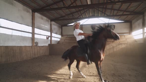 Сowboy on a Horse in the Hangar Man in the Cowboy Hat Riding a Horse in a Covered Hangar Horse alt