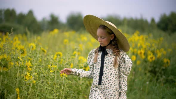 Cute Teen Girl in Hat Walking on Blossoming Sunflower Field alt
