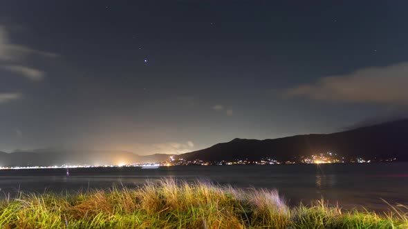Night Timelapse on the Shores of the Bay Overlooking the Mountains and Water with Ships alt