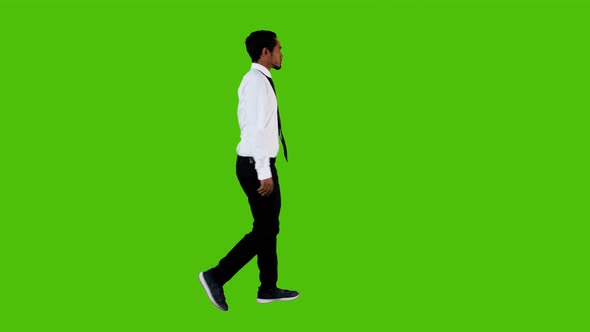 Happy young businessman walking and looking around over a green background.4K alt