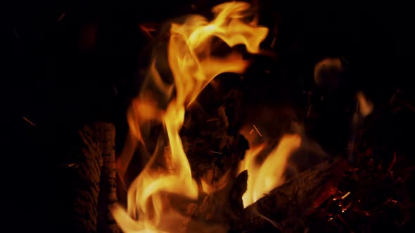 Burning red-hot sparks rise from large fire in the night sky, in slow motion. alt