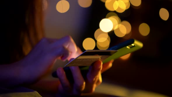 Close up shot of female hand holding credit card using smart phone for shopping online