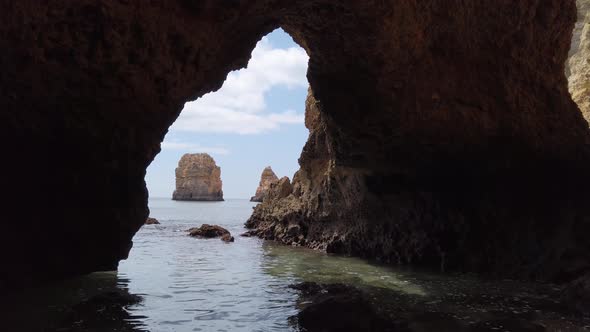 Viewing out the mouth of an Algarve sea cave to a limestone rock stack, Portugal. alt