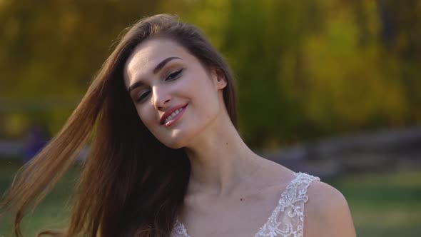 Portrait of Beautiful Brunette Woman with Long Hair Is Posing in Sunny Rays at Autumn Park alt