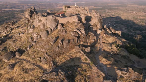 Drone flying over Monsanto castle ruins during sunrise, Portugal. Aerial forward tilt up reveal alt