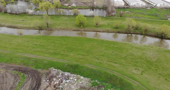 Trash Residues Next To Meadow Landscape By A Calm River alt