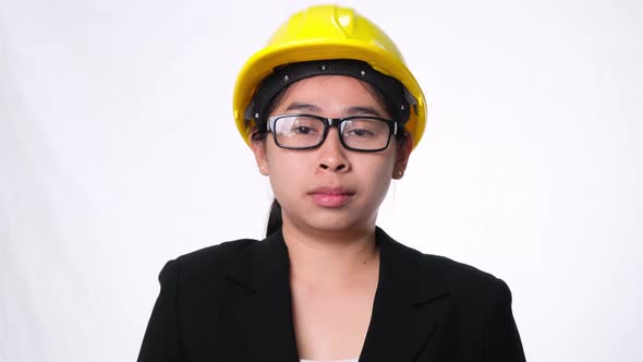 Female technician in helmet standing thumbs down, showing disapproval on white background. alt