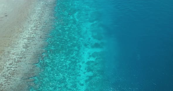 Dive boat over tropical coral reef and turquoise blue water, aerial view