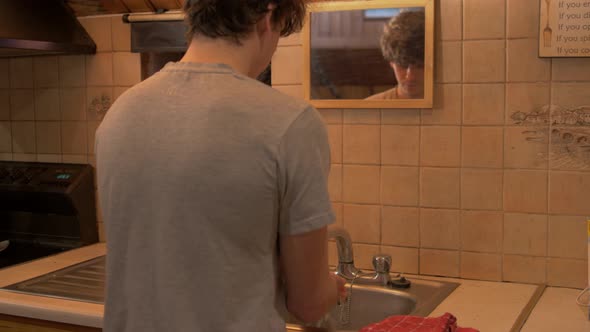 Young man walks up to sink washes hands walks off alt