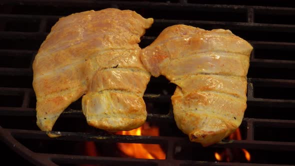 Closeup of the Raw Chicken Fillet Frying on the Grill Grid in Flames alt