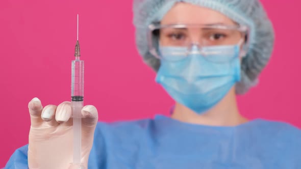 Professional Female Doctor Holds a Syringe with a Vaccine on a Pink Background alt