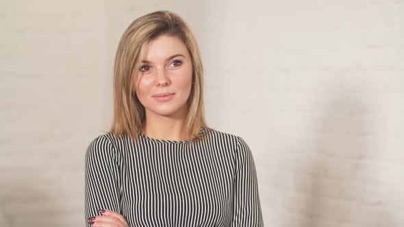 Blonde Business Woman Smiles at Camera with Colleagues Working in Background alt