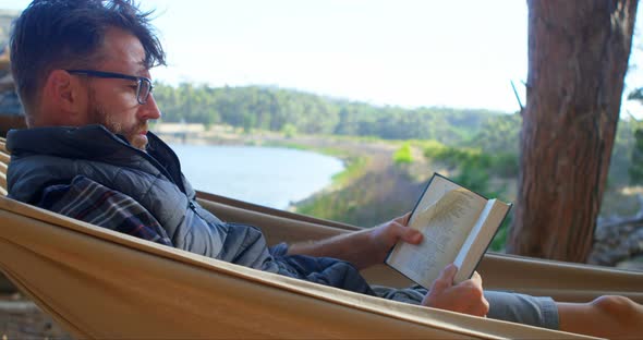 Man Reading a Book While Relaxing in A Hammock 4k alt