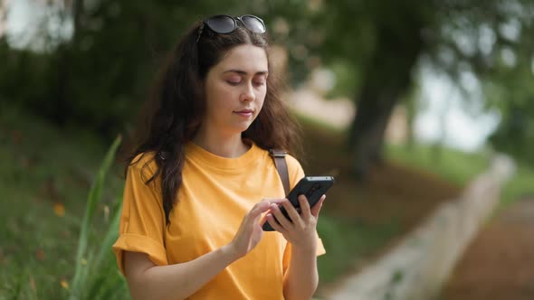 Portrait of a young smiling woman typing on a smartphone. Online surfing alt