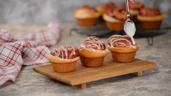 Pouring Icing Over Swirl Buns with Jam alt