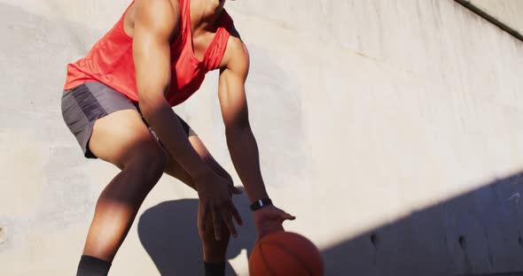 Fit african american man exercising outdoors in city, bouncing basketball alt