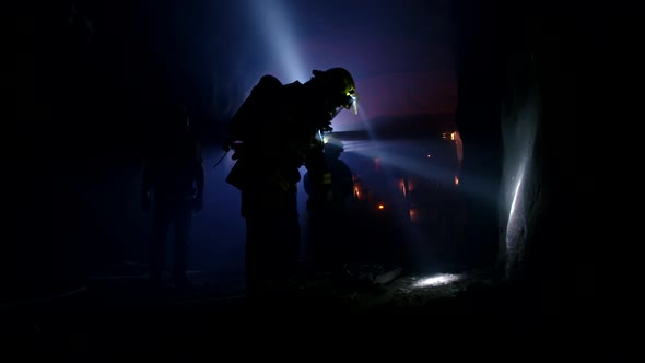 Rescue forces search for survivers inside a dark tunnel using flashlights alt