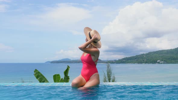 Woman in Red Swimwear Relax in Swimming Pool with Sea View alt