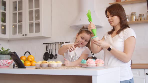 Mother and Daughter Icing Cupcakes and Having Video Call