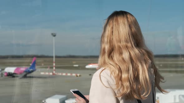 woman looks at planes standing on the airport runway