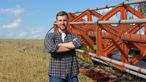 Farmer in Wheat Field with Combine Harvester Harvesting in Background alt