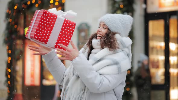 A Woman is Standing in a Snowcovered Square of the City alt