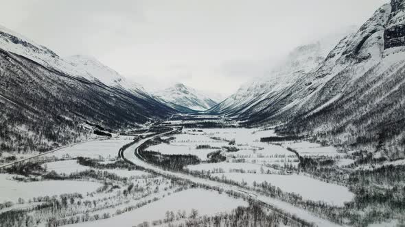 Snow-covered Manndalen valley in winter with steep dramatic mountains; aerial alt