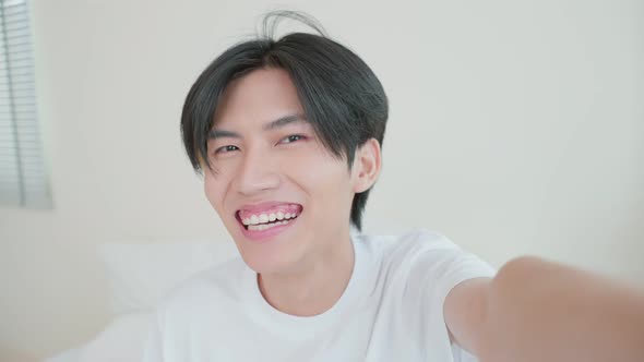 Asian handsome man gay use mobile phone video call online with family. alt
