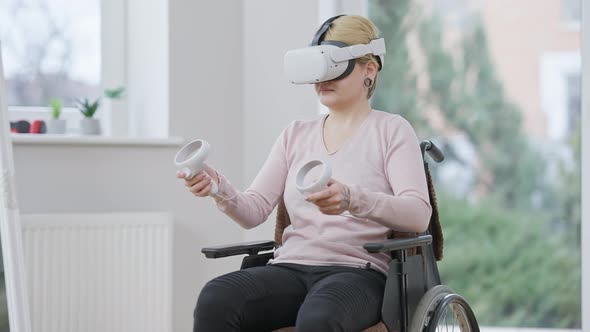 Active Young Paraplegic Woman Using Virtual Reality Headset Sitting on Wheelchair Indoors alt