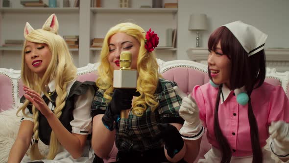 Carefree Cute Multiracial Women in Cosplay Costumes Having Fun Singing Karaoke alt
