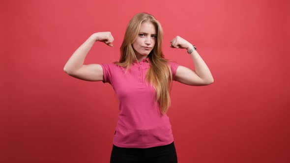 Young Woman Points To the Strong Hands on a Red Background alt