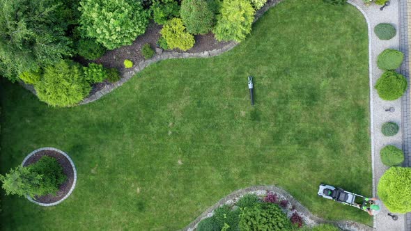 Man Cutting Grass With Electric Mower. alt