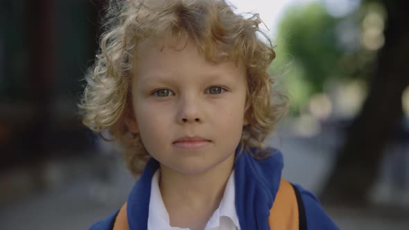 Close Up Portrait of Joyful Schoolboy Standing on School Yard with Bag Turn Around Smilling and alt