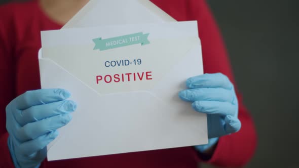Woman Holding Positive Antigen Detection Test for Covid-19 alt