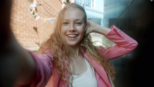Portrait of Happy Blonde Making Online Video Call Chatting and Sending Air Kiss Outdoors in Street alt