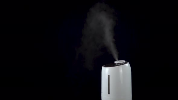 An Ultrasonic Humidifier Humidifies a Room with a Strong Stream of Steam on an Isolated Black alt