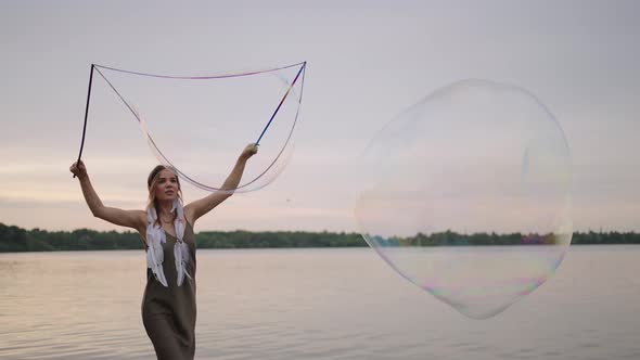 A Young Girl Artist Shows Magic Tricks Using Huge Soap Bubbles alt